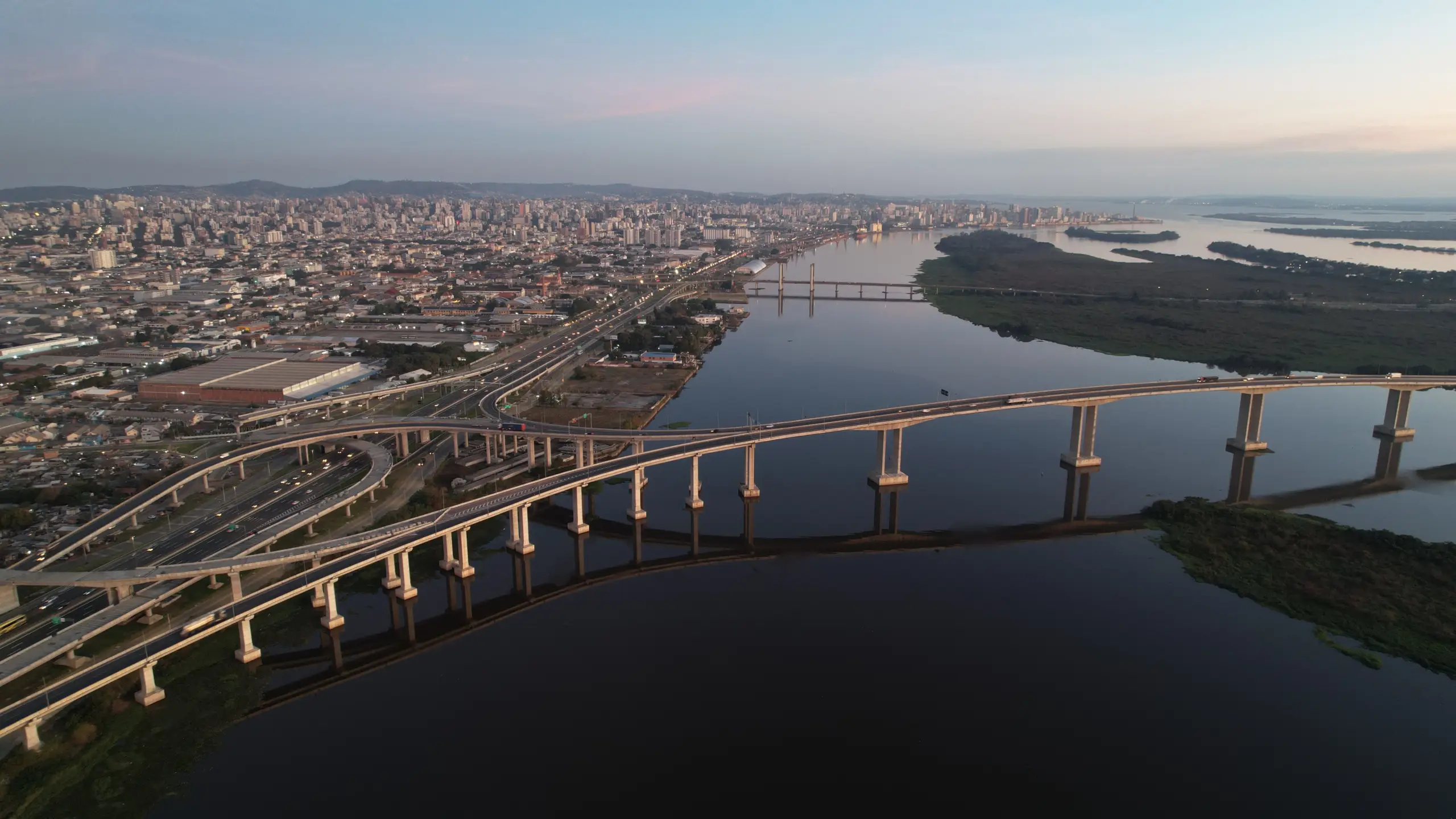 Imagem aérea feita com drone da ponte do Guaíba em Porto Alegre. No horário do pôr do sol e com a cidade no plano de fundo.